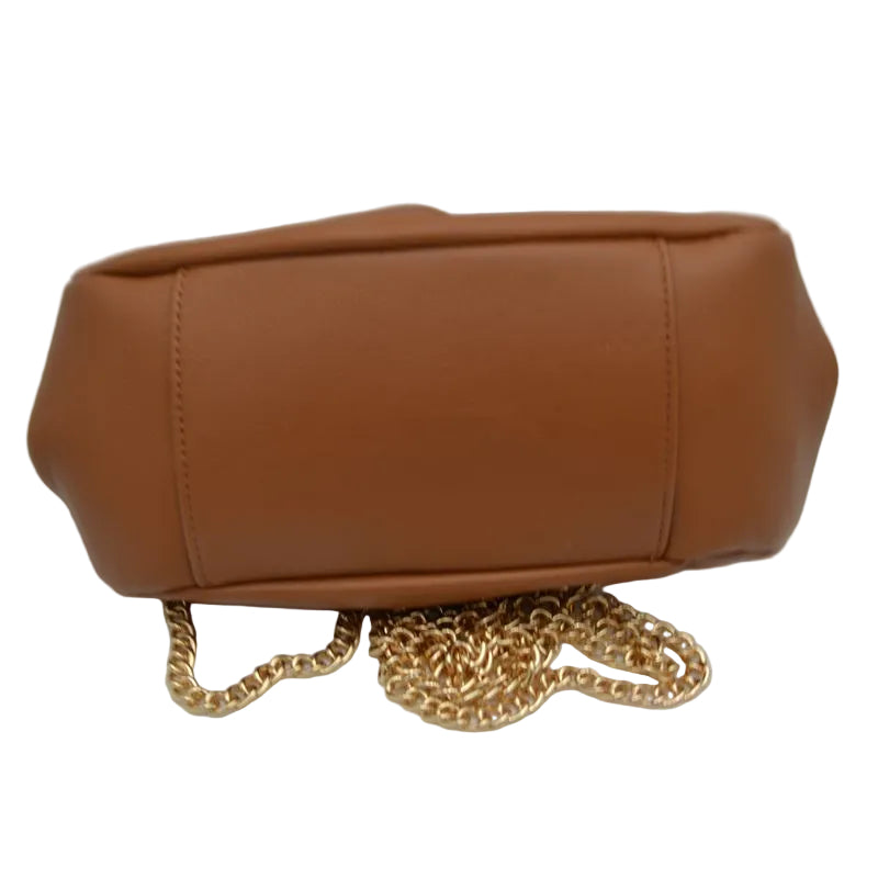 A tan faux-leather handbag shown from the back, featuring a gold-tone chain strap resting on a white surface.